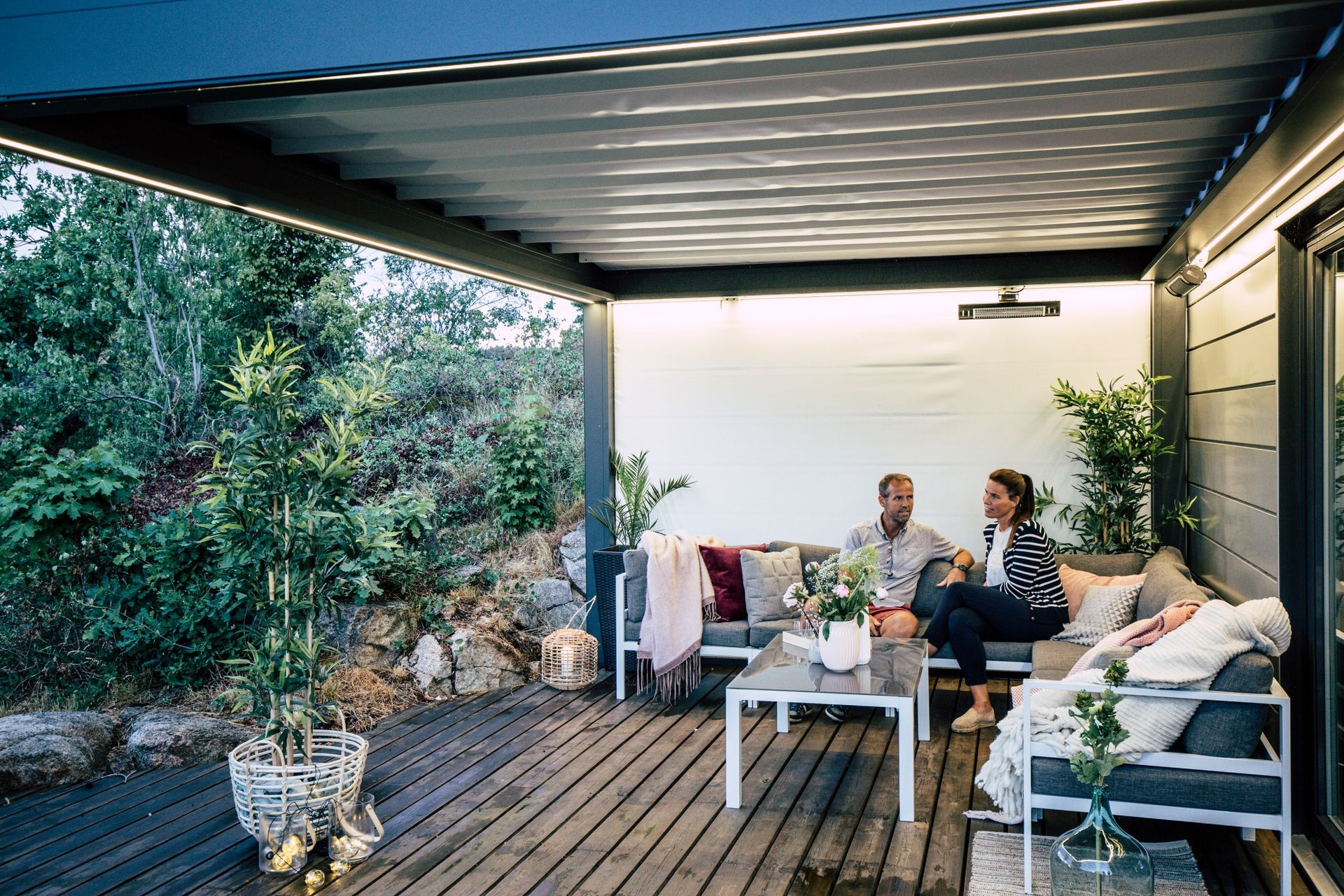 Couple sitting on a cozy outdoor patio with modern furniture and plants.