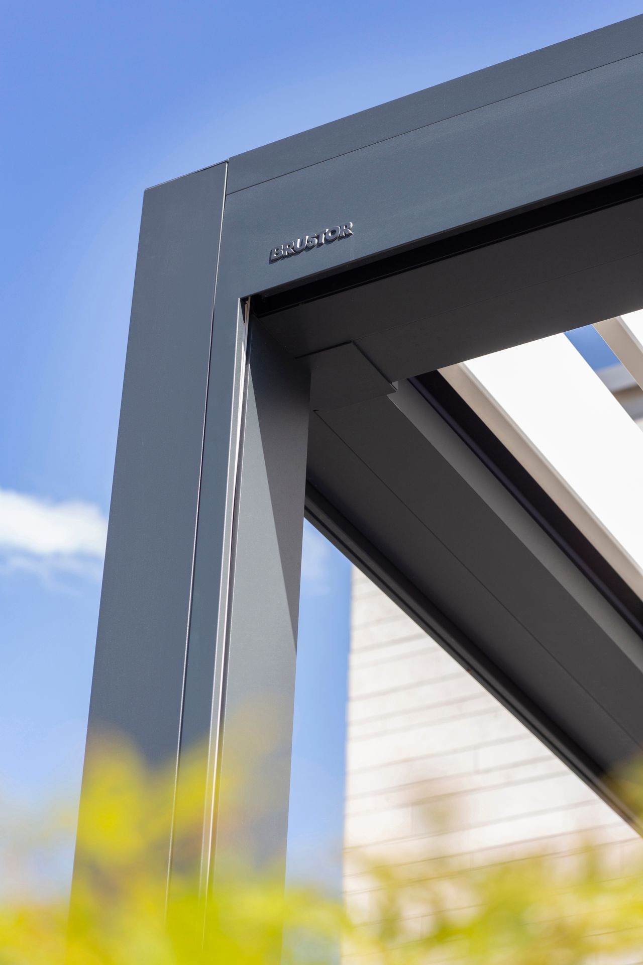 Close-up of a modern outdoor metal pergola frame against a clear blue sky.