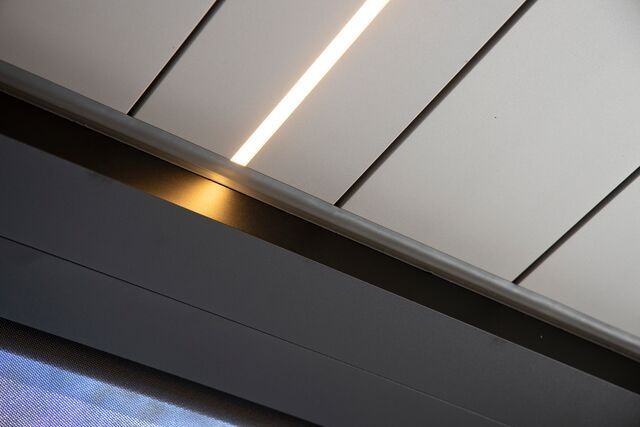 Close-up of a ceiling with linear recessed lighting and sleek panels, showcasing modern interior design.